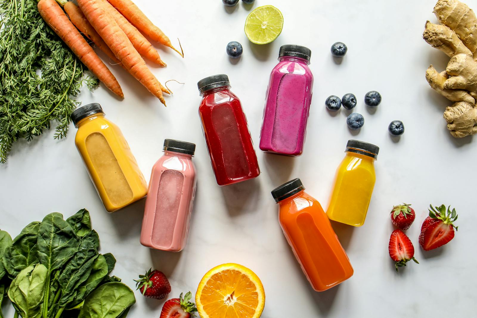 Colorful bottled smoothies with fresh carrots, berries, and citrus